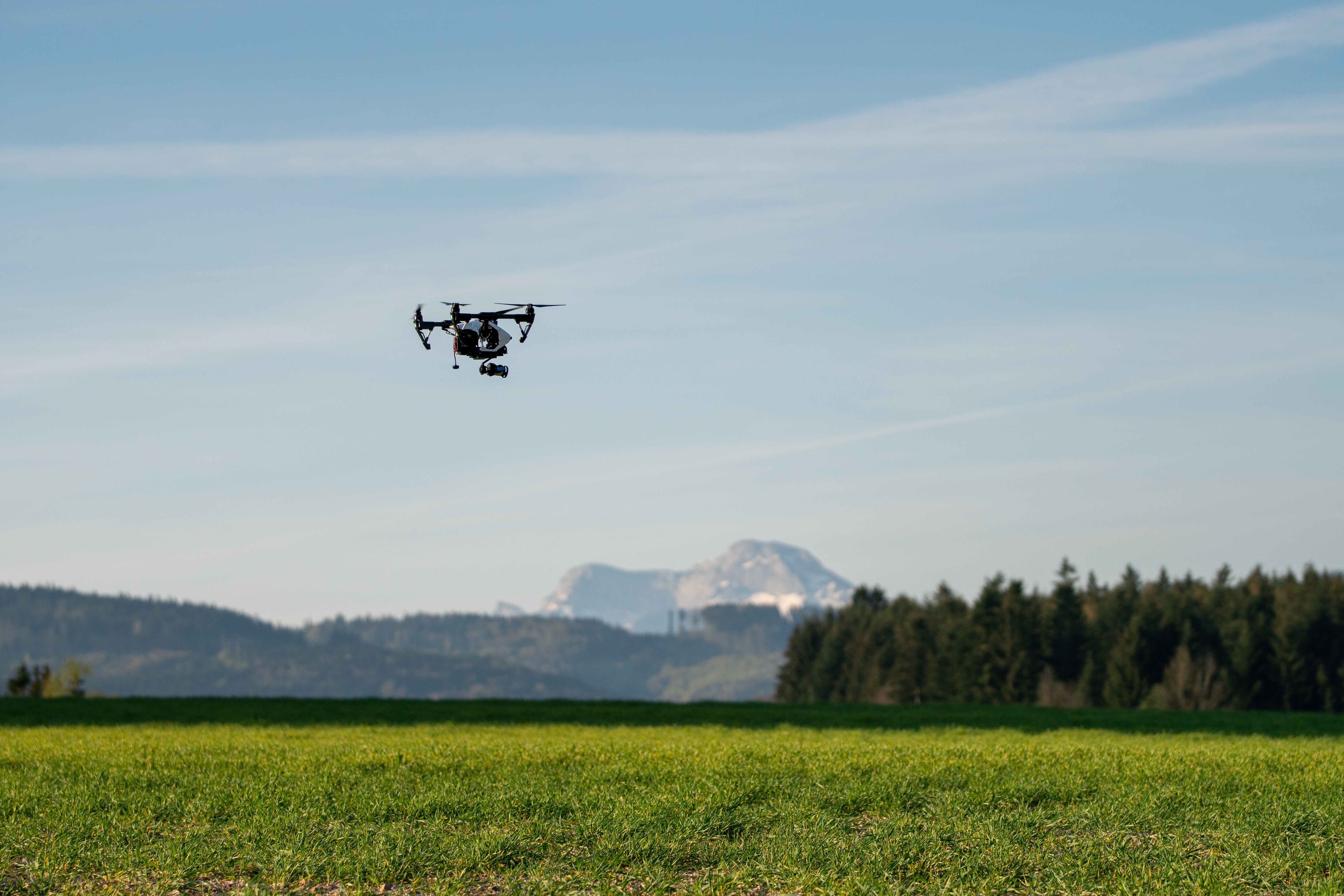 Quadrocopter flying over a green field